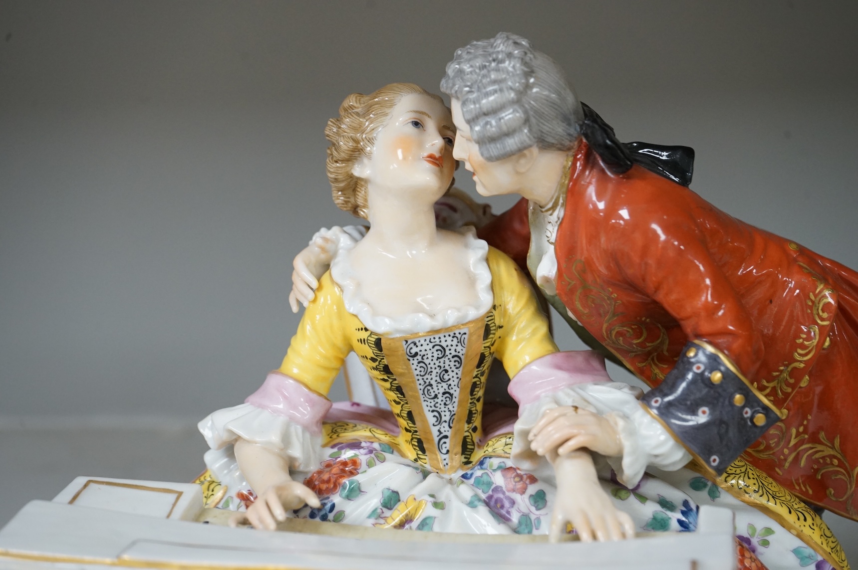 A large German porcelain group lovers at a piano, 22cm high